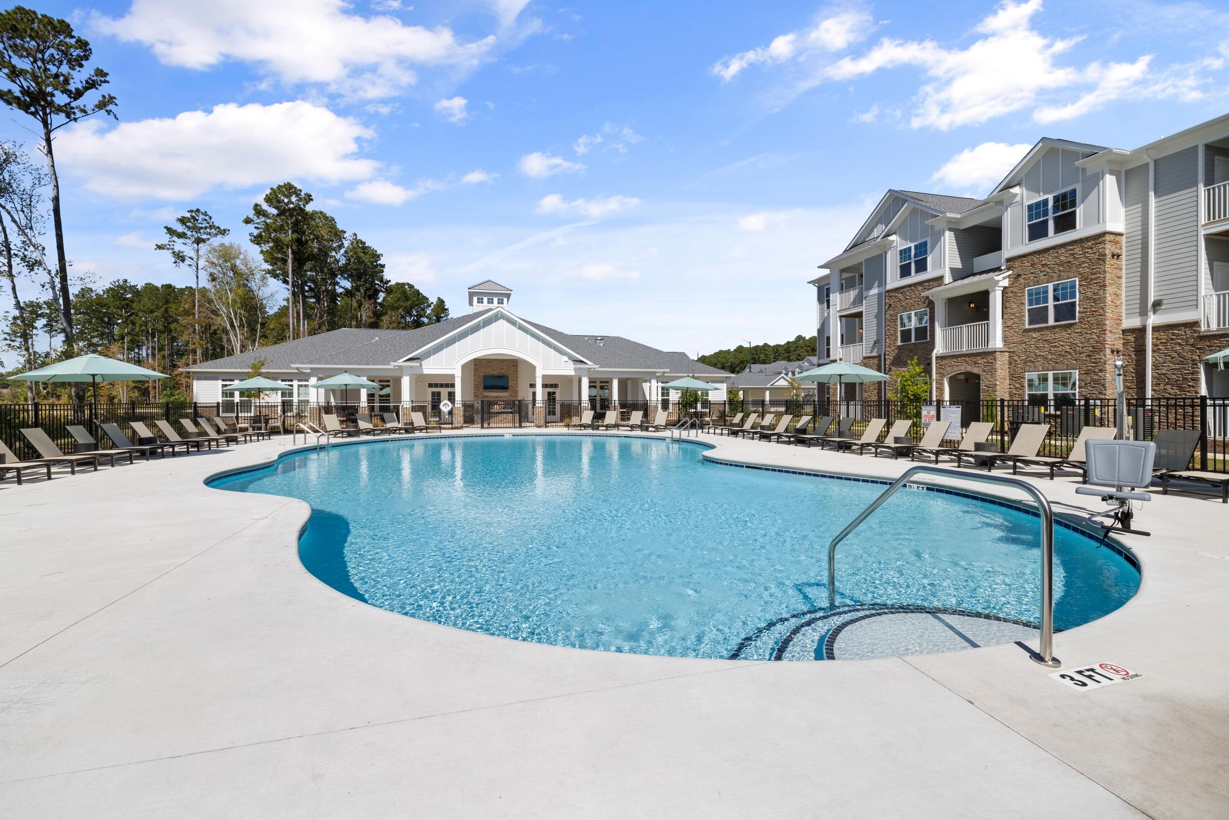 Side View of the Swimming Pool Surrounded by Lounge Chairs and a Building in the Background.