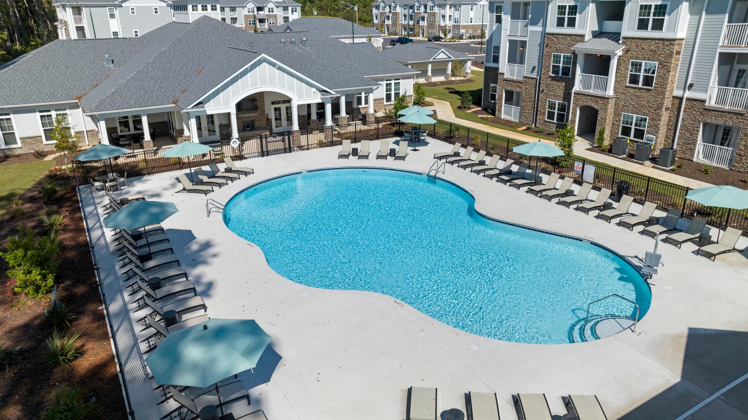 Large Swimming Pool Surrounded by Lounge Chairs and Umbrellas.