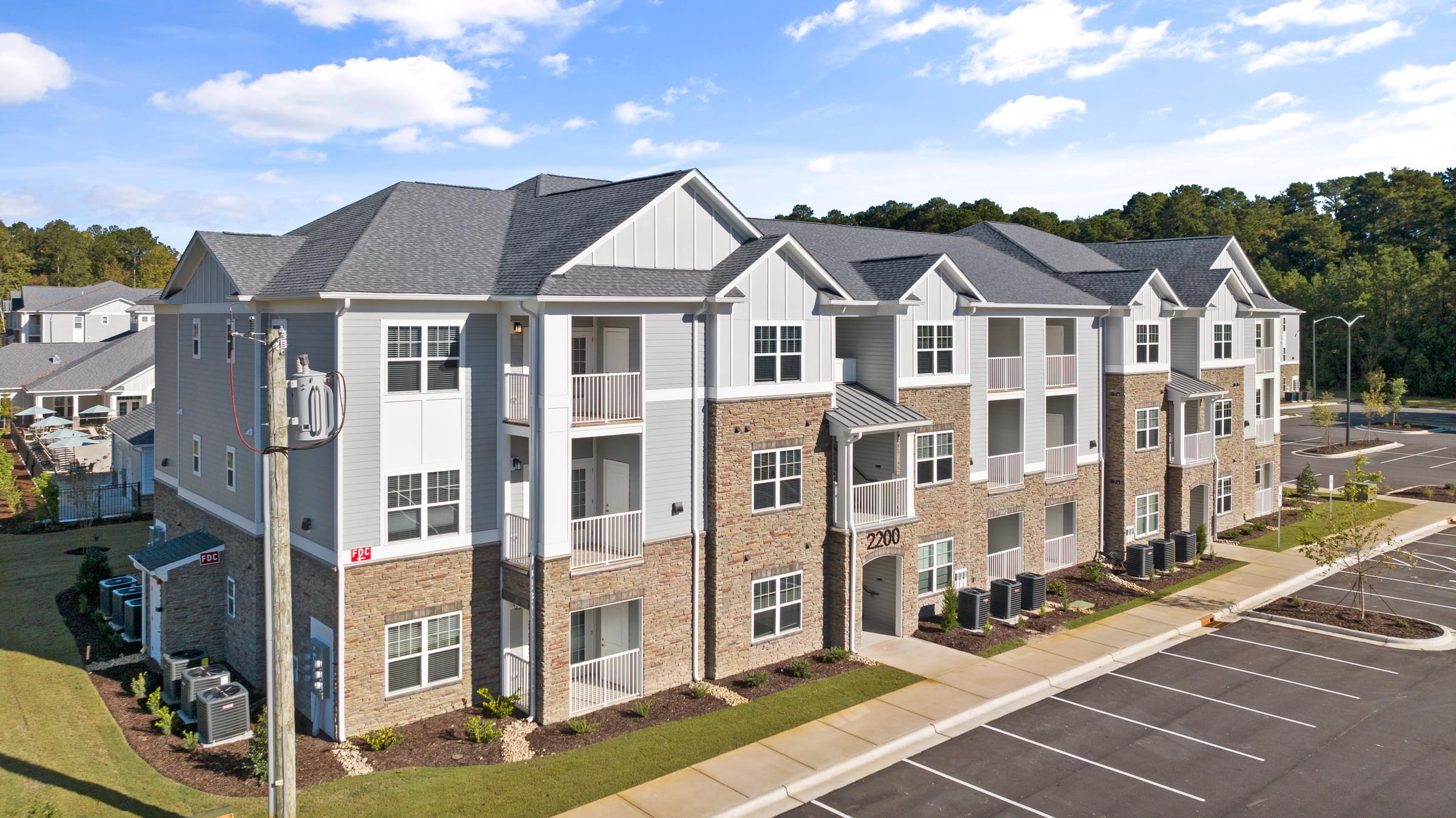 Exterior of Complex with Grey and White Coloring and a Parking Lot in Front.