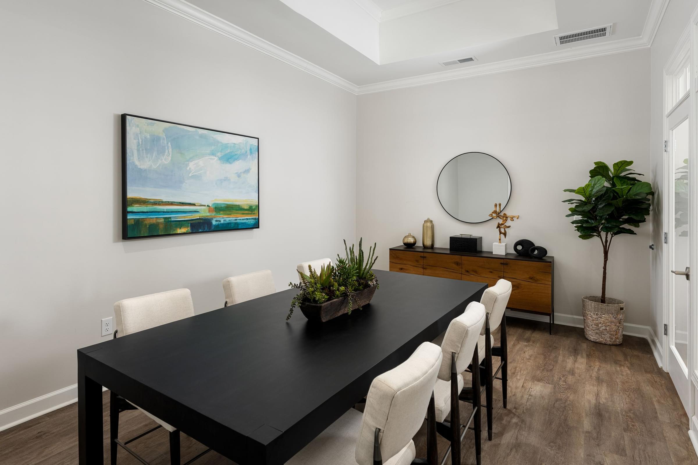 A dining room with a black table and white chairs.