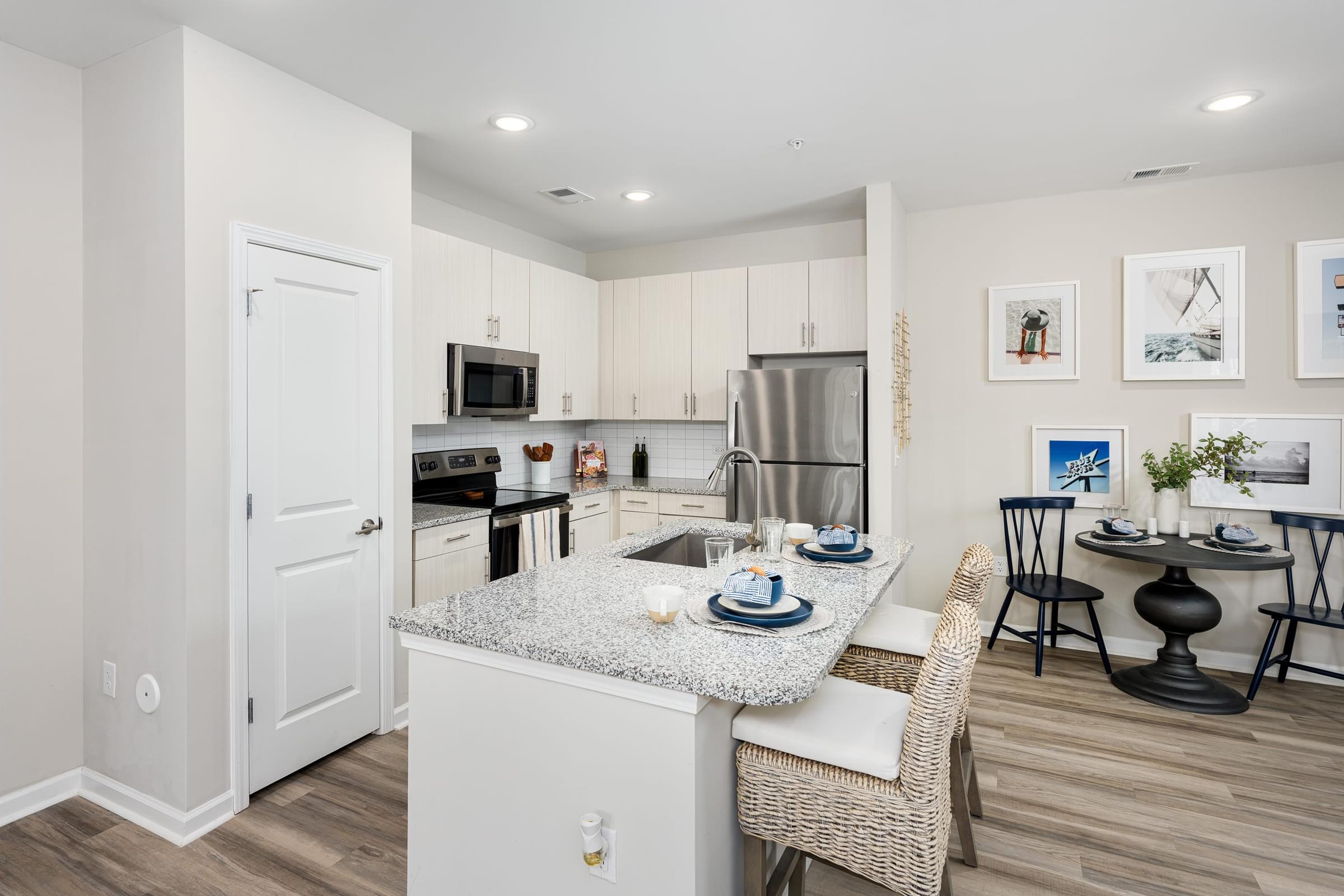A kitchen with a table set for two and a dining area.