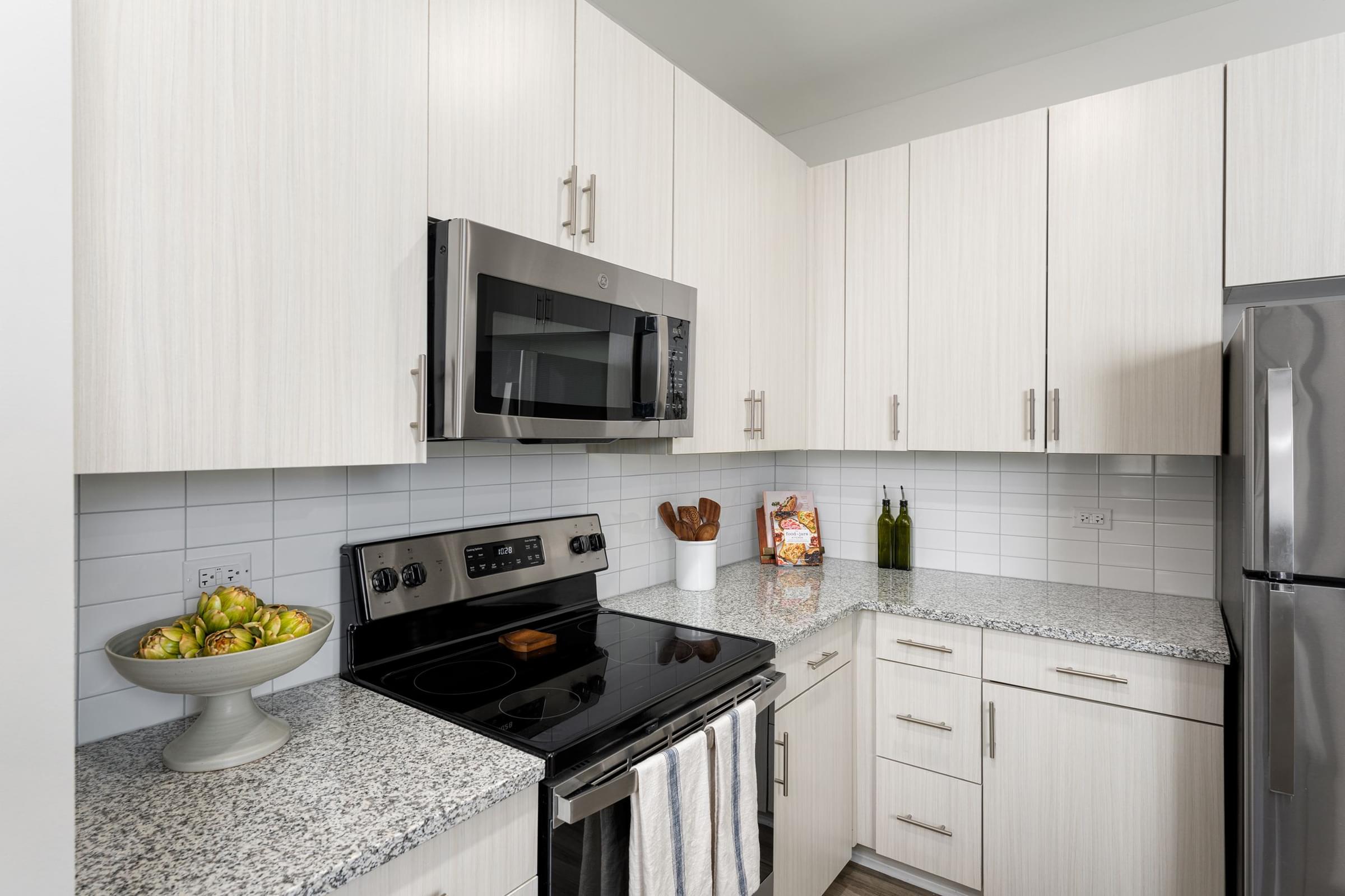 A kitchen with a black stove top oven and a microwave above it.