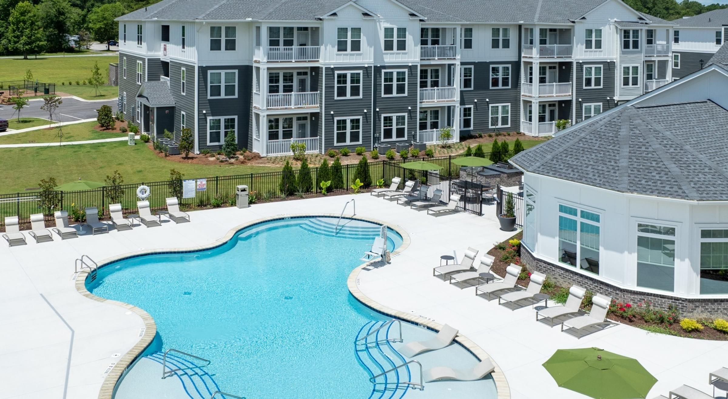 Large Swimming Pool Surrounded by Lounge Chairs in Between the Buildings.