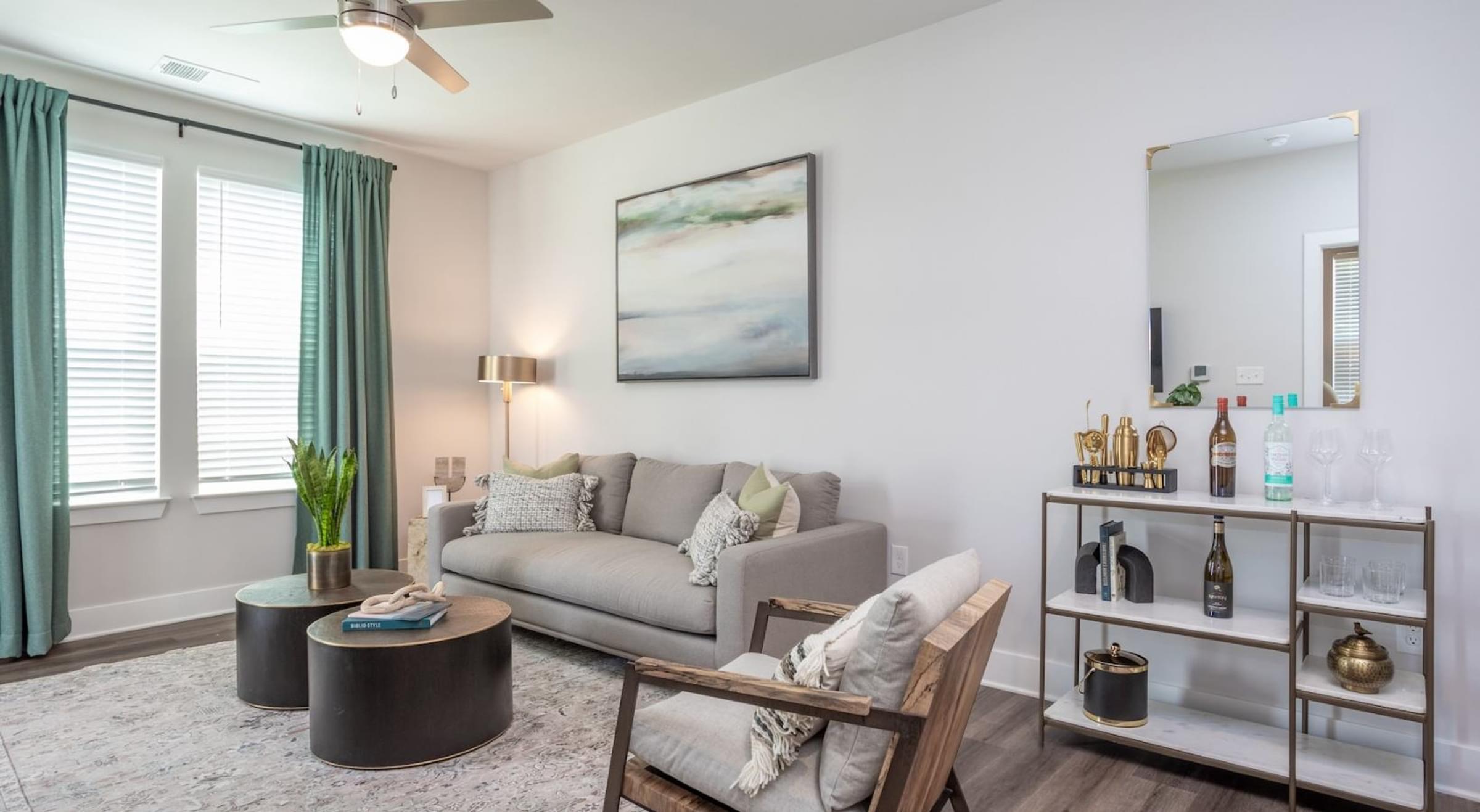 Living Room with a Grey Couch, Sitting Chair, a Black Coffee Table with a Painting on the Wall.
