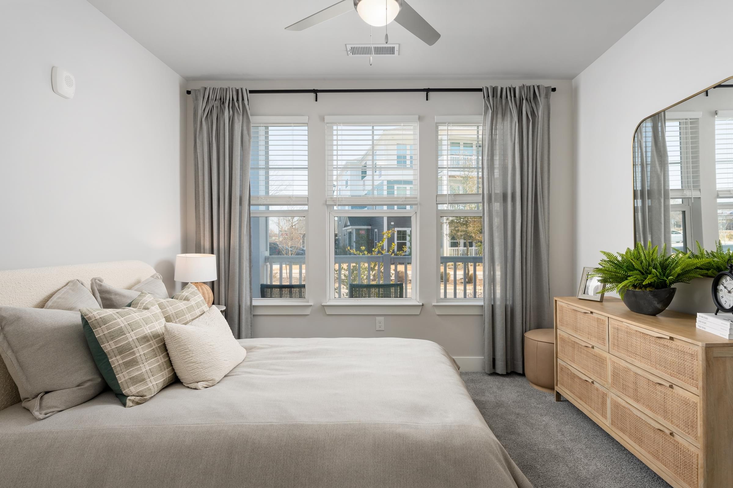 A bedroom with a large bed, a dresser, and a window with curtains.