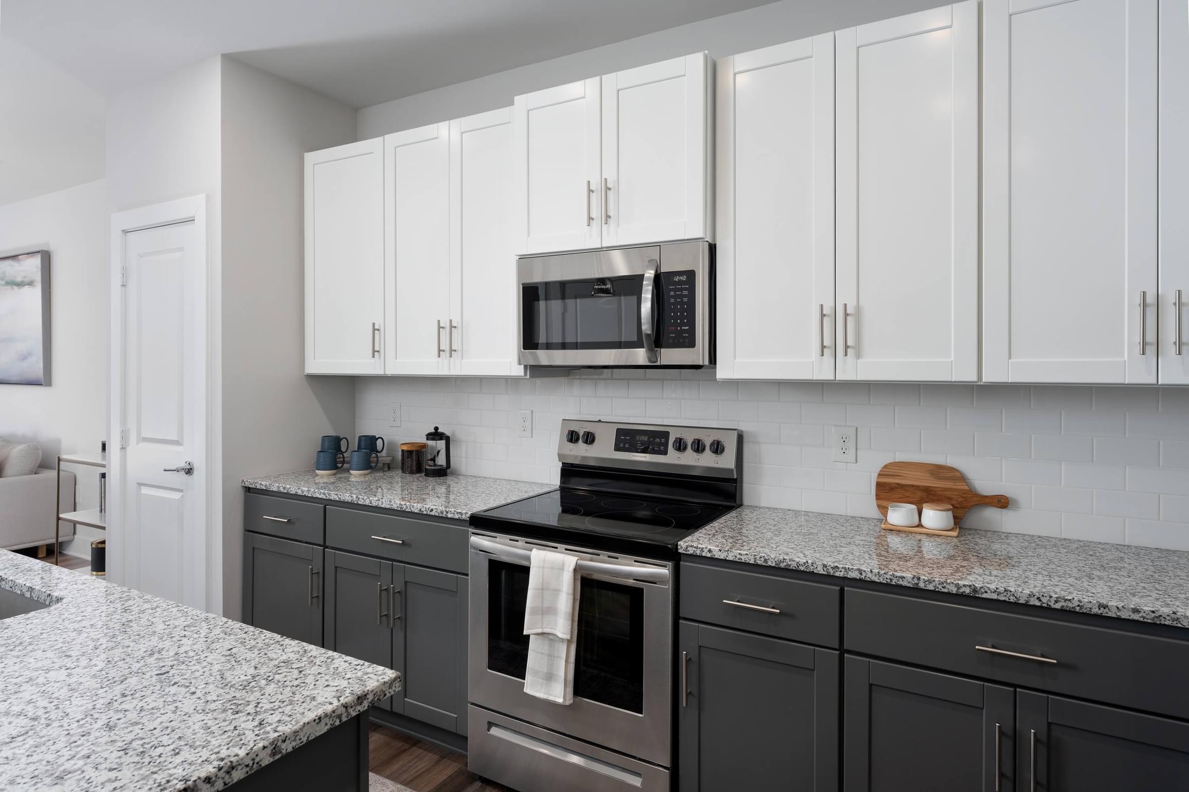 A kitchen with white cabinets and a granite countertop.
