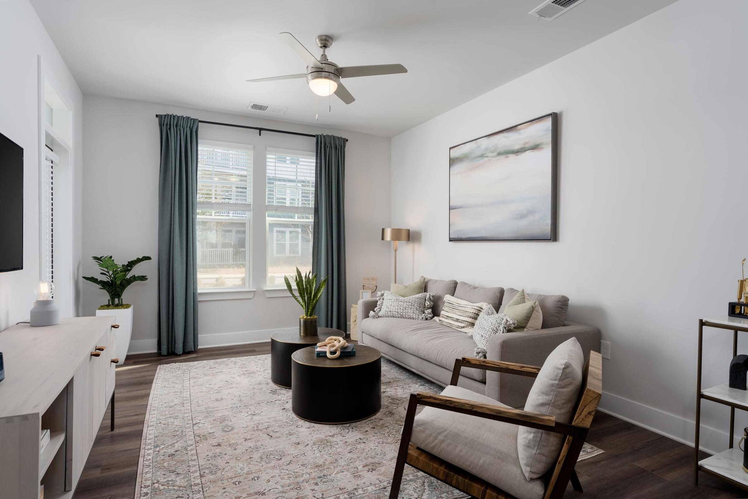 A living room with a grey couch, a coffee table, and a ceiling fan.