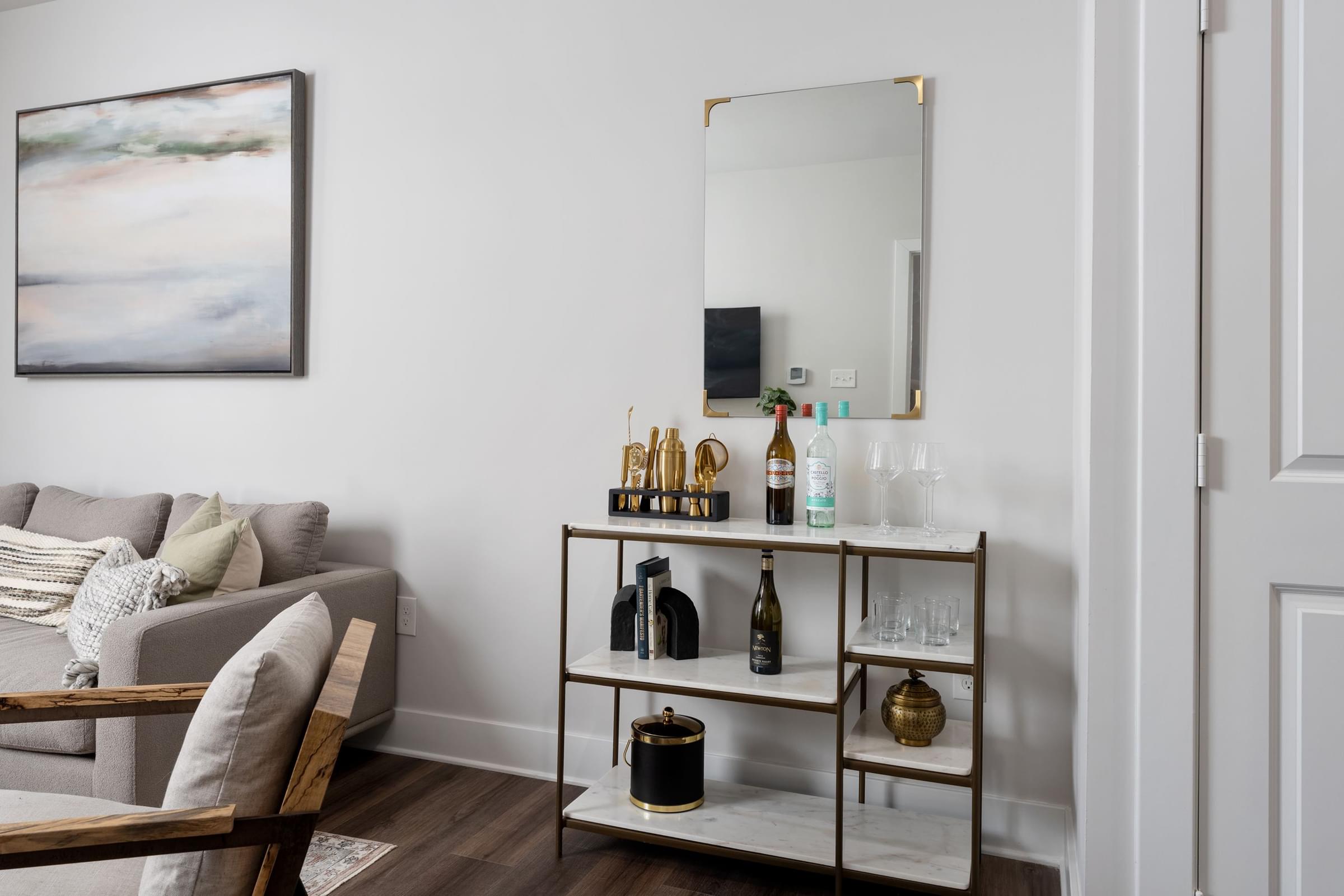 A living room with a grey couch, a gold shelf, and a painting on the wall.