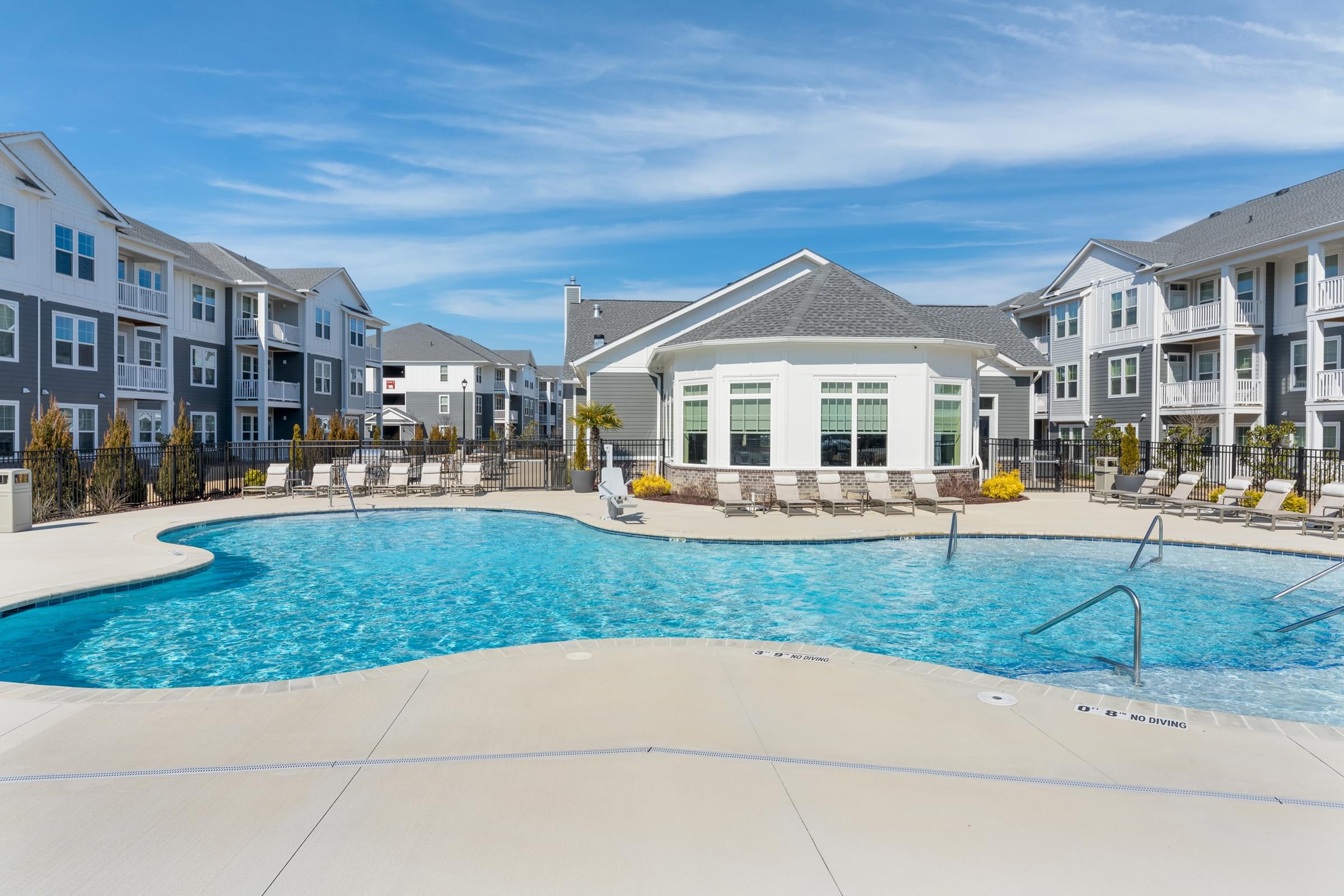 A large swimming pool in front of a building with a white and grey facade.