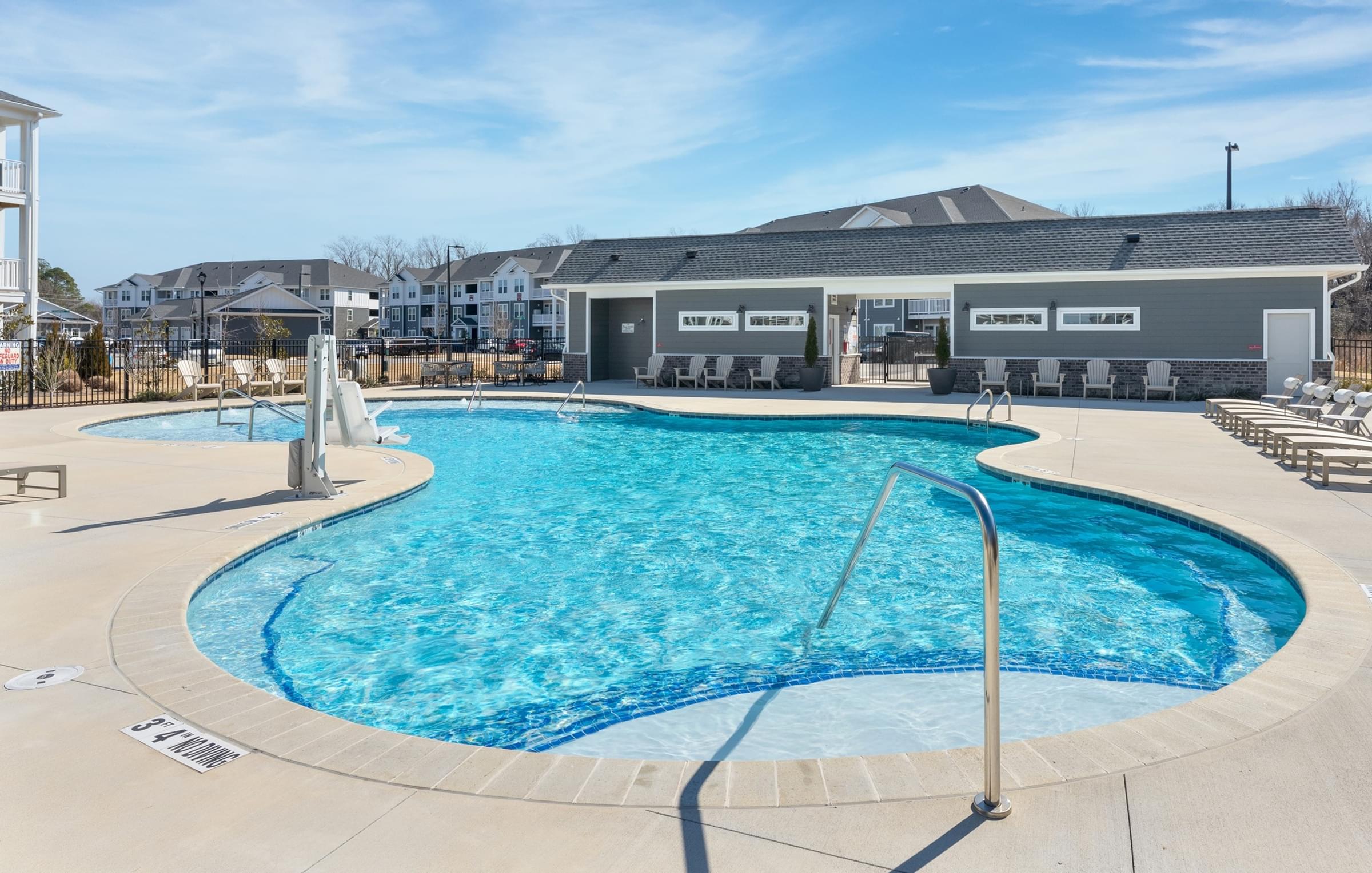 A large outdoor swimming pool with a slide and a building in the background.