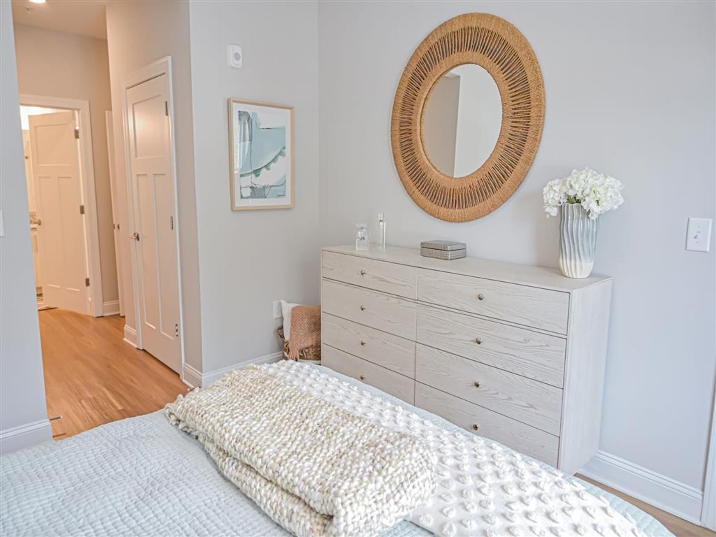 a white bedroom with a bed and a mirror