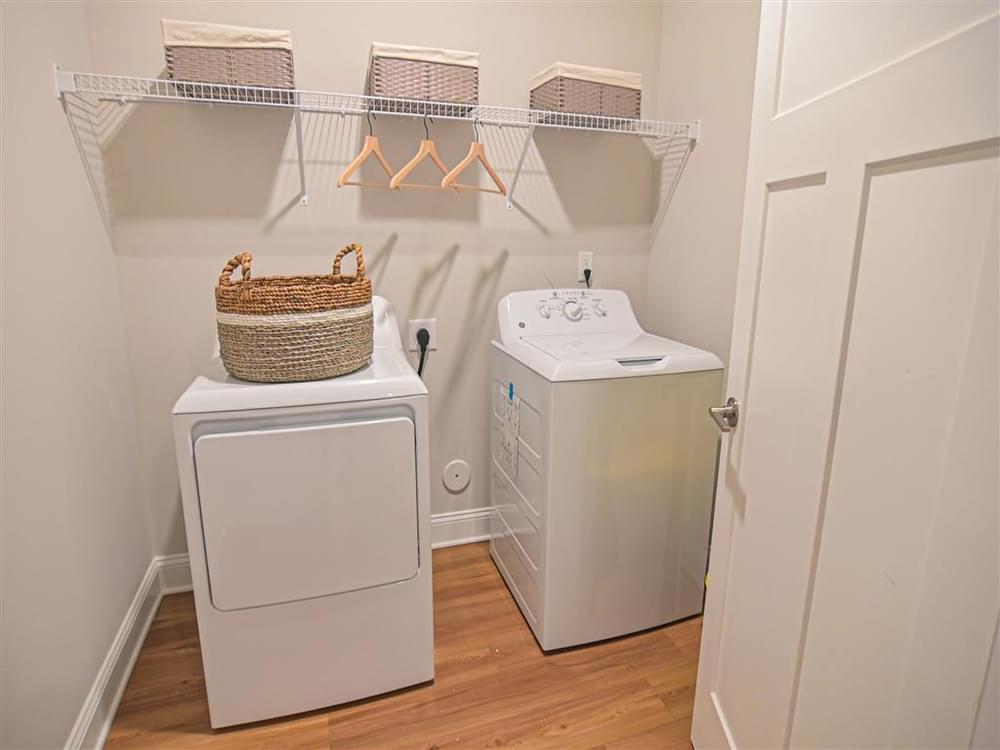 a laundry room with a washer and dryer and a shelf with baskets