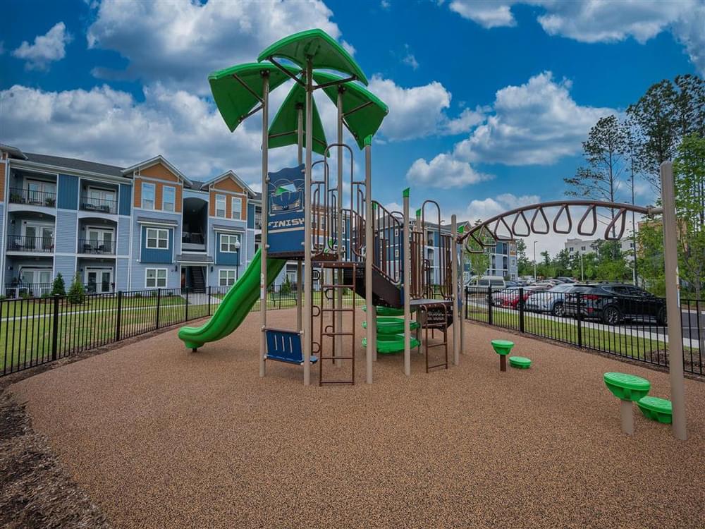 a playground with a slide and other playground equipment in front of apartments