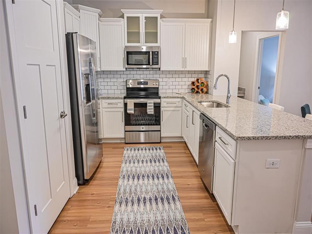 a white kitchen with a rug in the middle