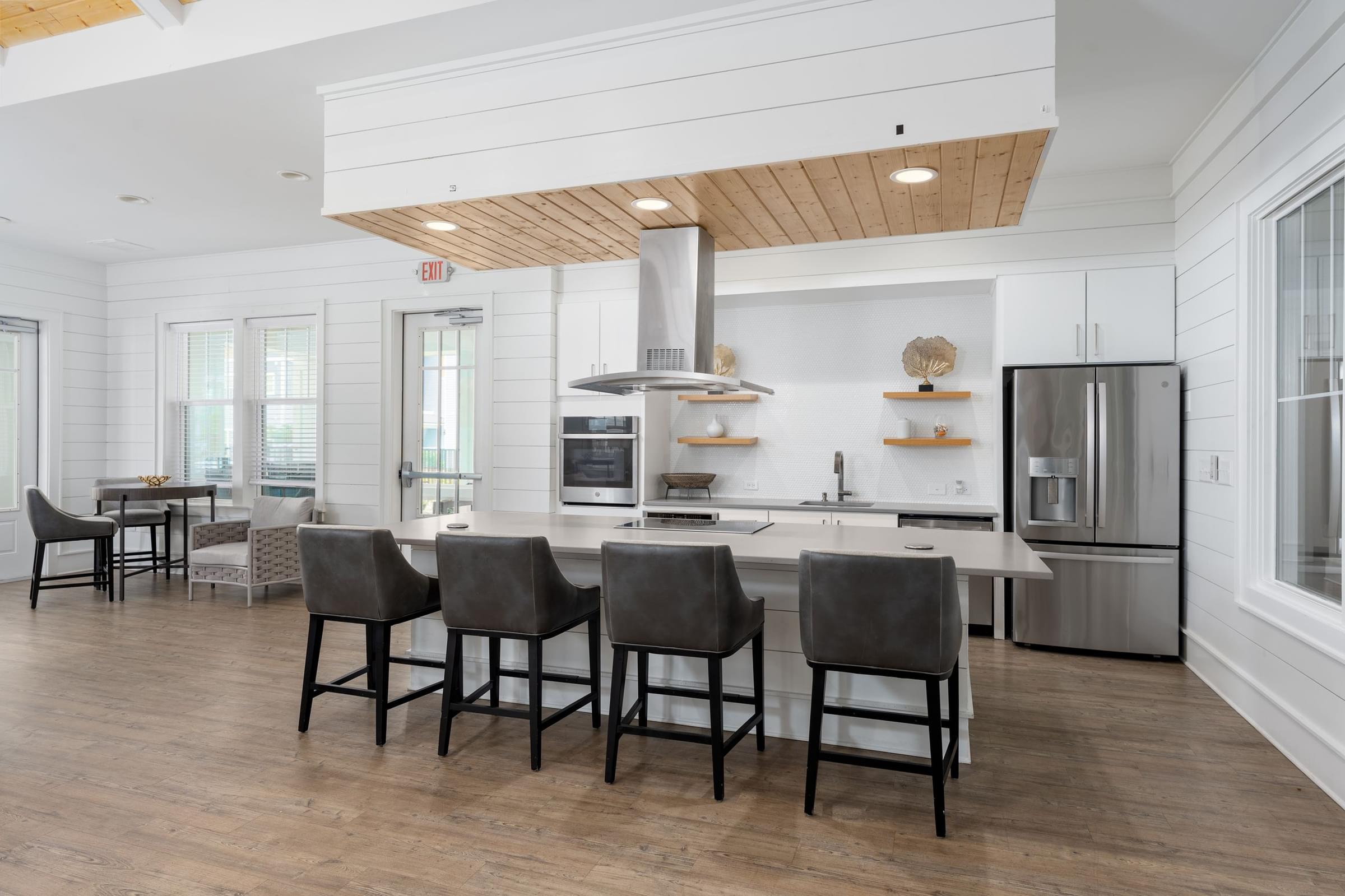 A kitchen with a white color scheme and wooden beams on the ceiling.