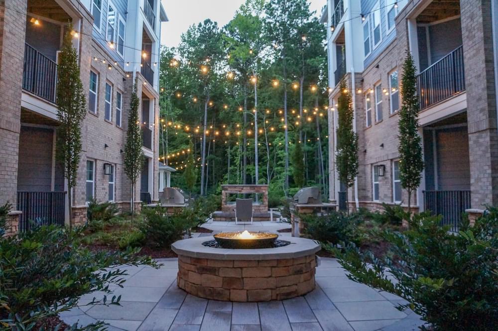 a courtyard with a fire pit and strings of lights
