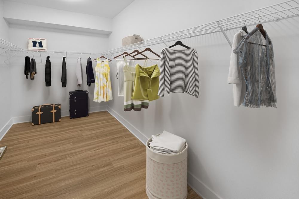 a room with clothes hanging on a rack and a trash can