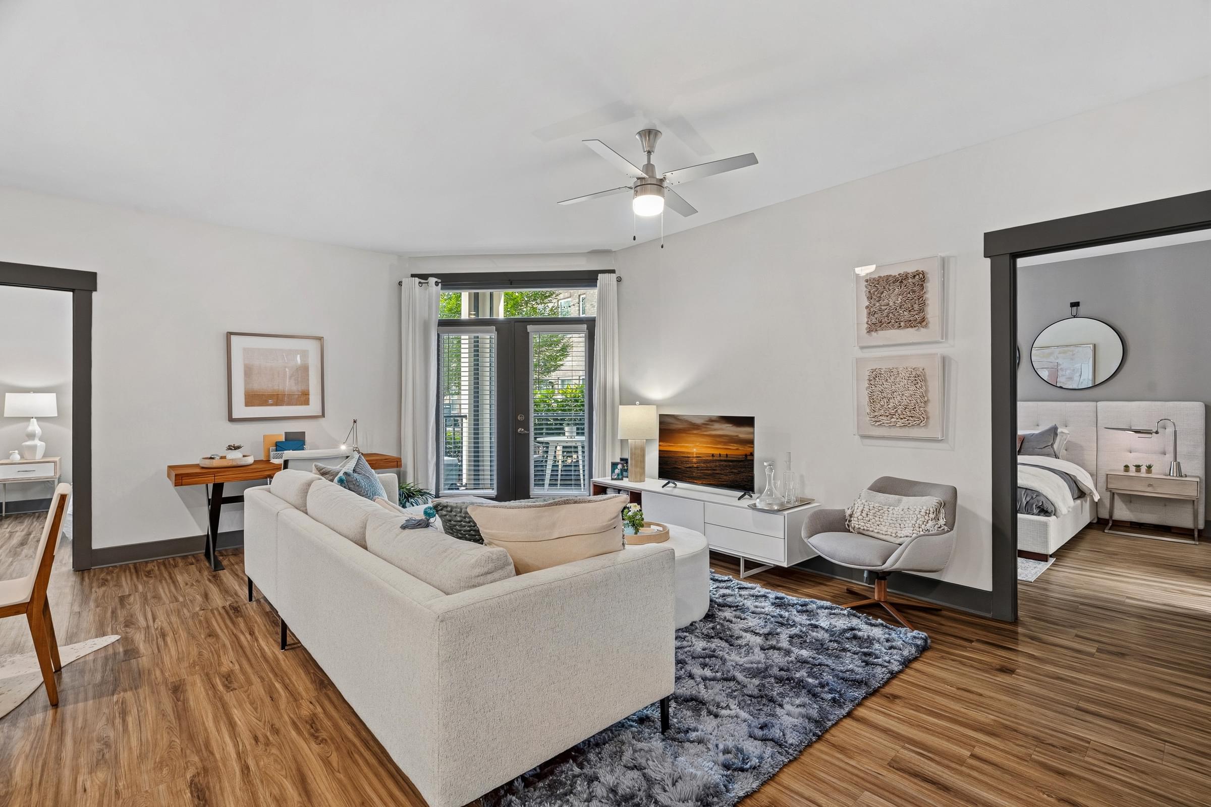 A living room with a white couch and a blue rug.