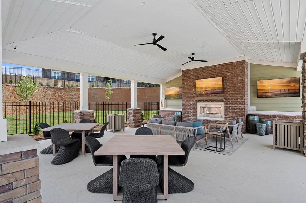 a covered patio with tables and chairs and a brick fireplace