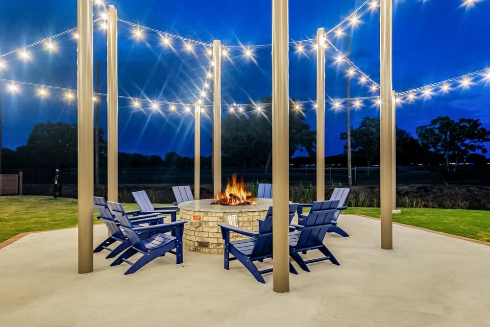 a patio with chairs and a fire pit at night