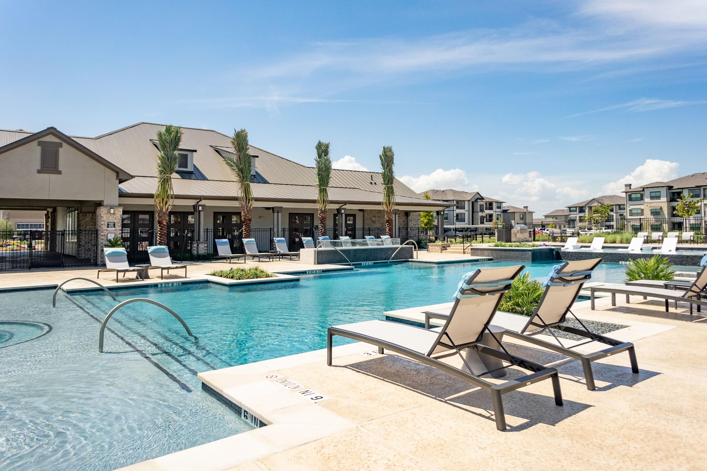 a swimming pool with lounge chairs and a building in the background