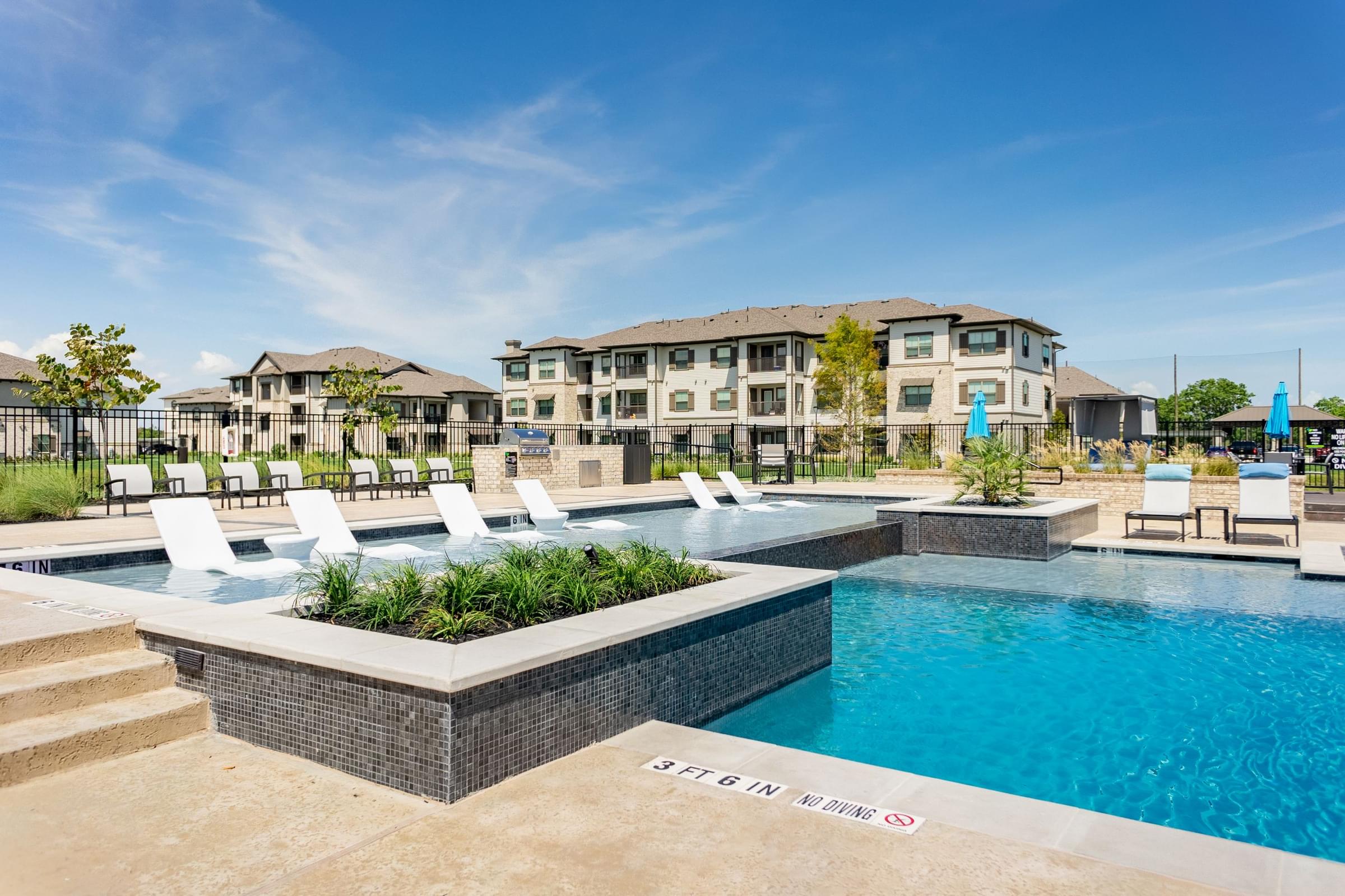 a swimming pool with white chairs and a building in the background
