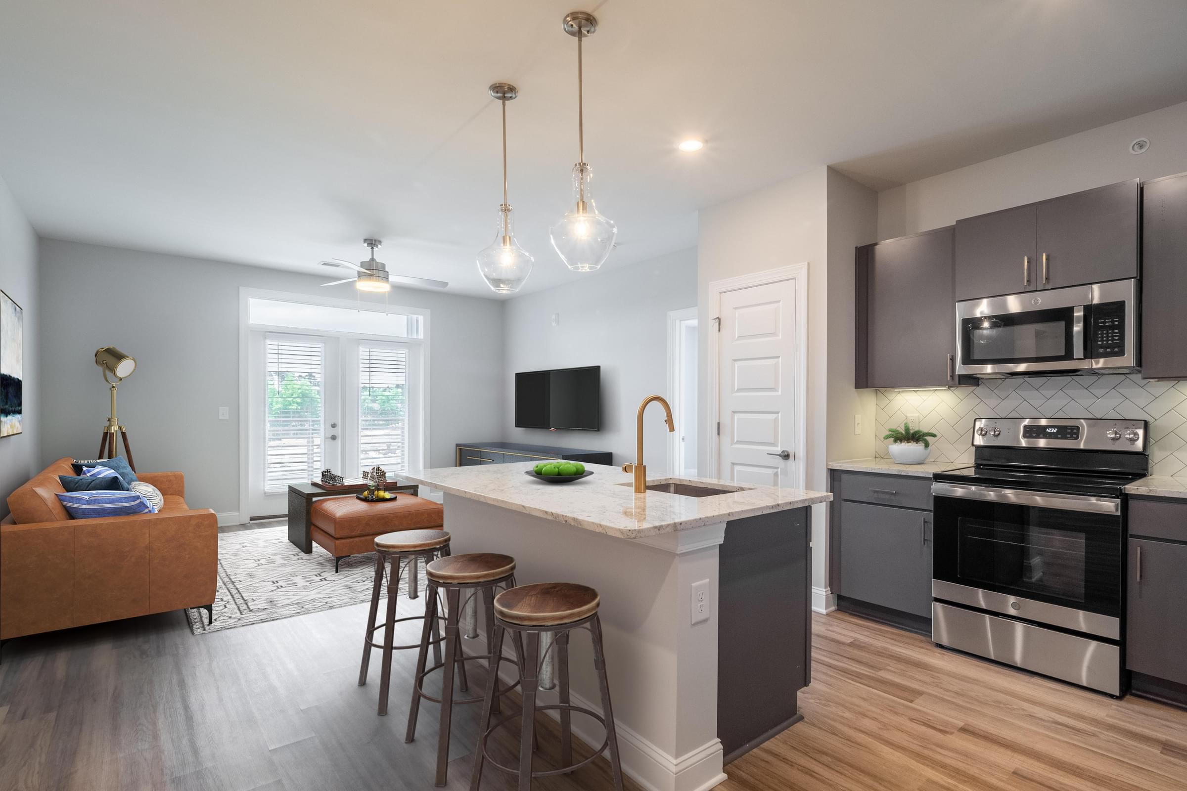 a kitchen with an island and stools in front of a living room with a couch and