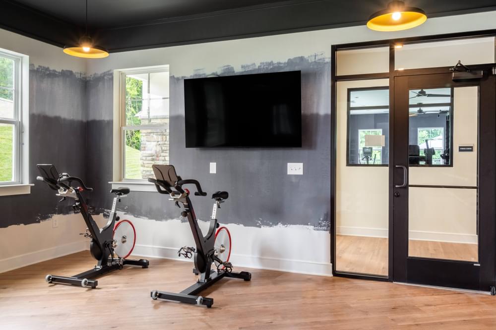 a home gym with two bikes and a tv on the wall
