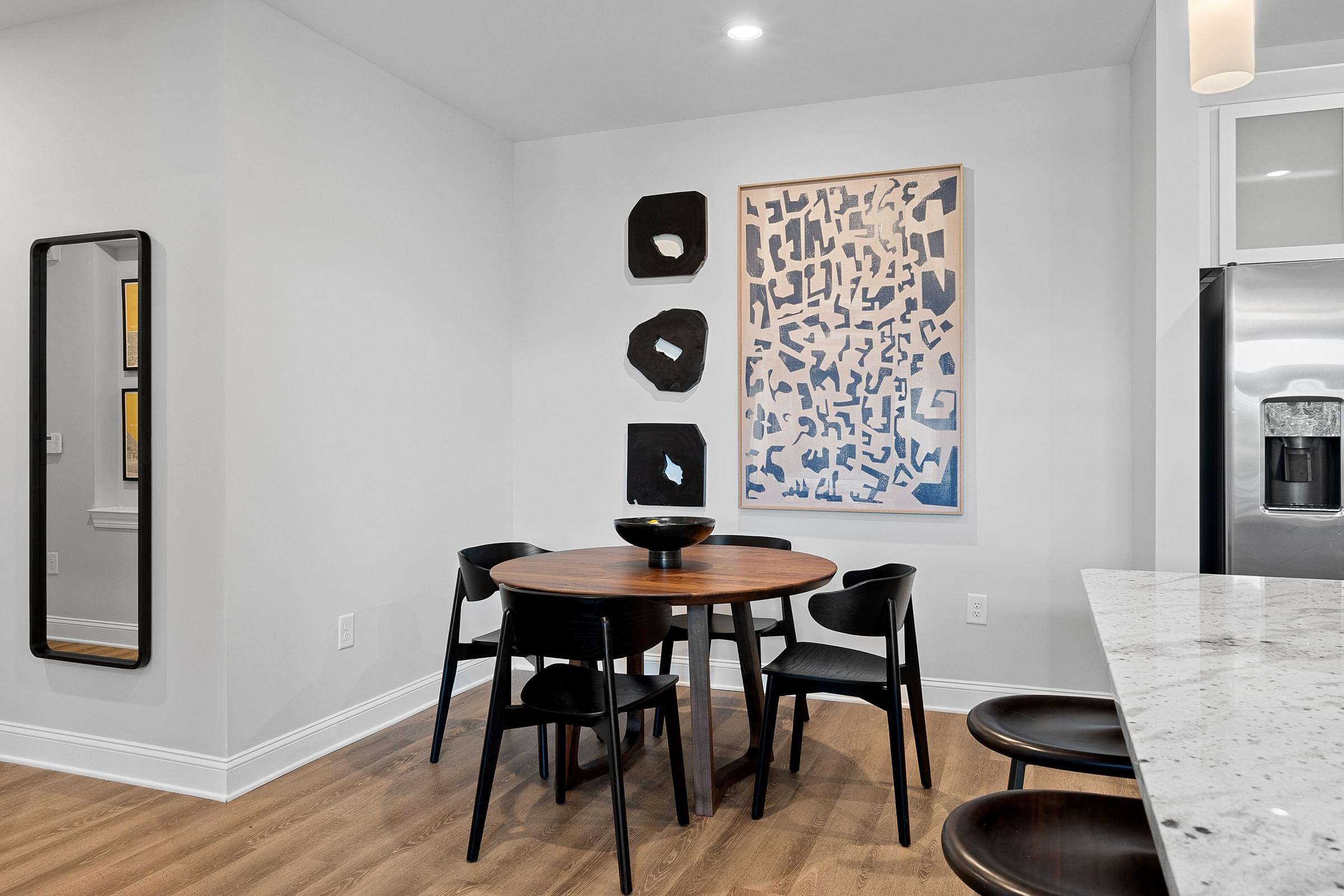 a dining area with a round table and four black chairs
