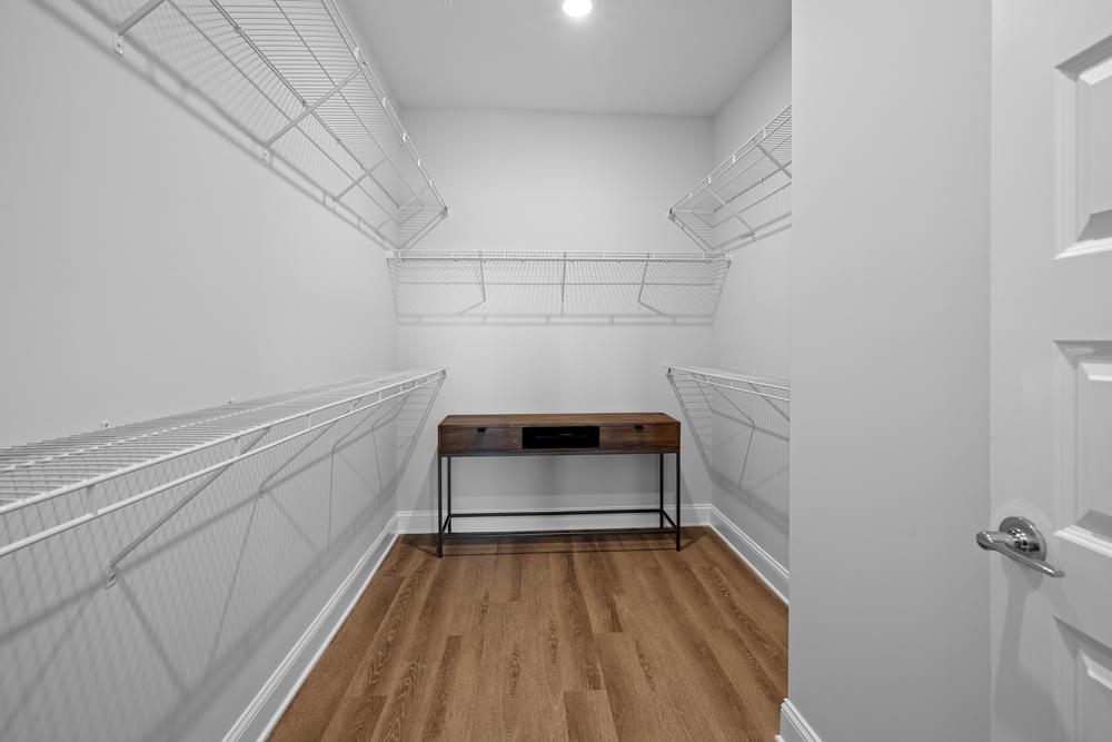 a spacious walk in closet with white walls and a wooden floor