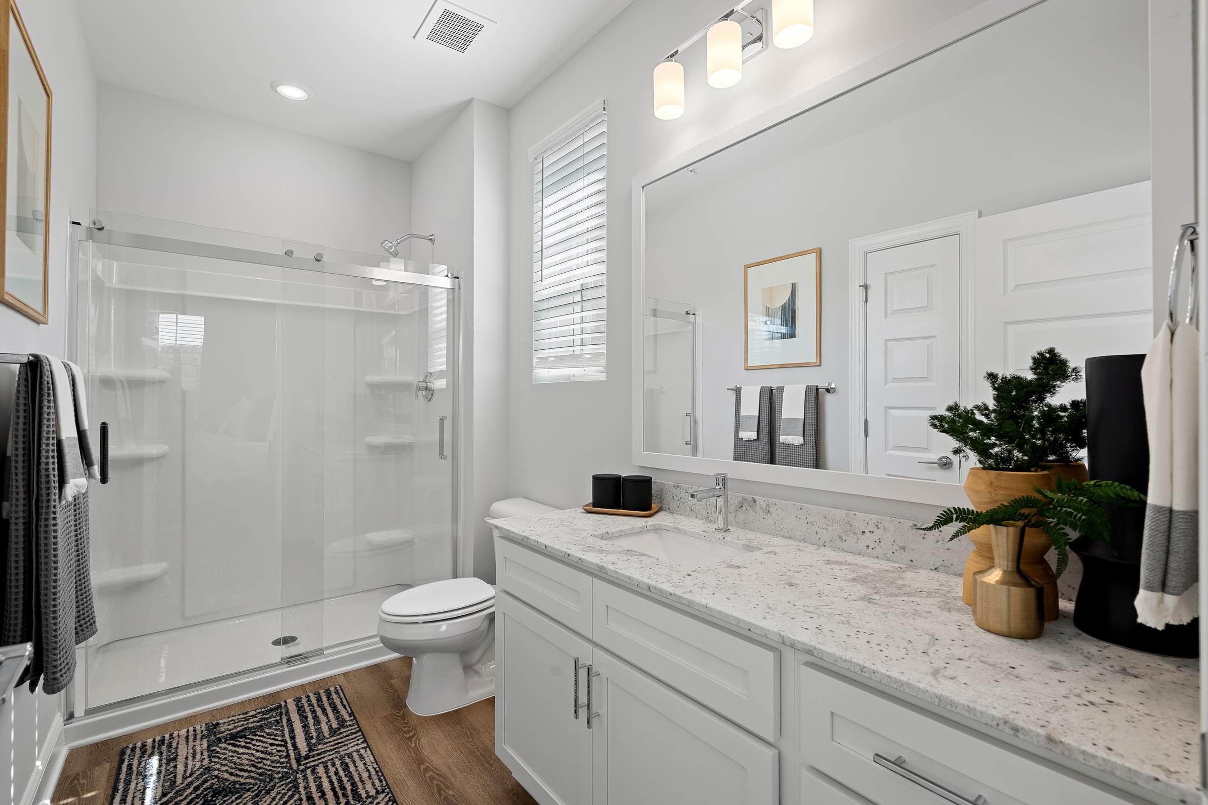 Spacious Bathroom with Walk-in Showers, Glass Sliding Doors, Granite Countertops, and Rain Shower Heads