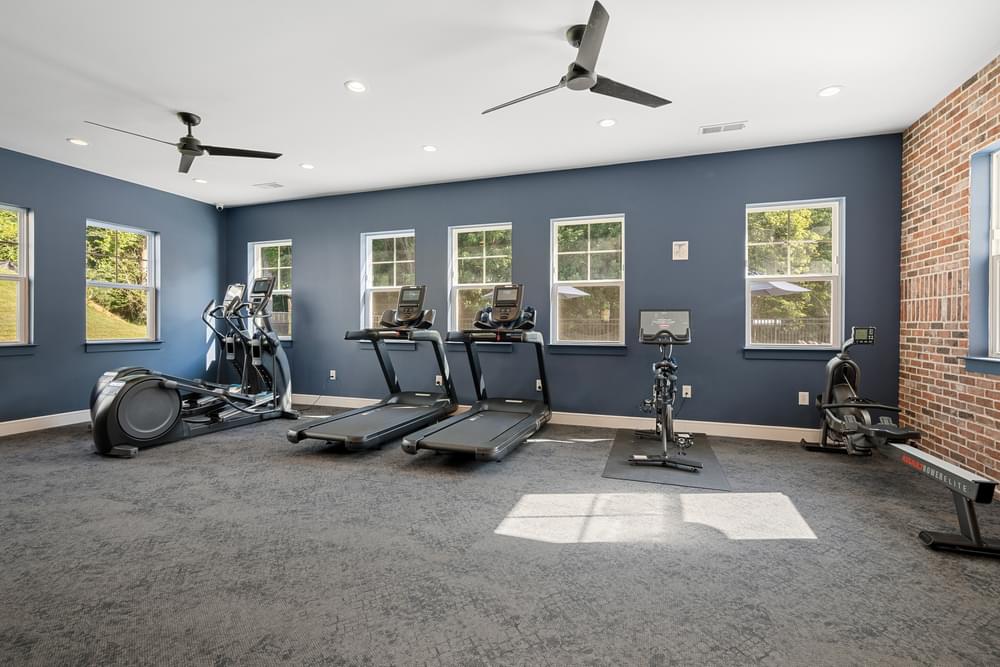 a gym with cardio equipment and a brick wall