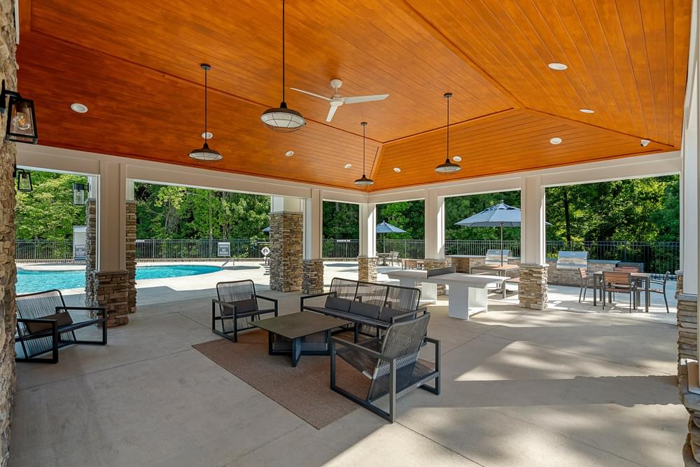 a covered patio with a wood ceiling and a pool in the background