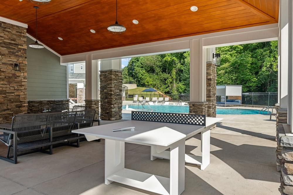 a patio with a ping pong table and a pool in the background