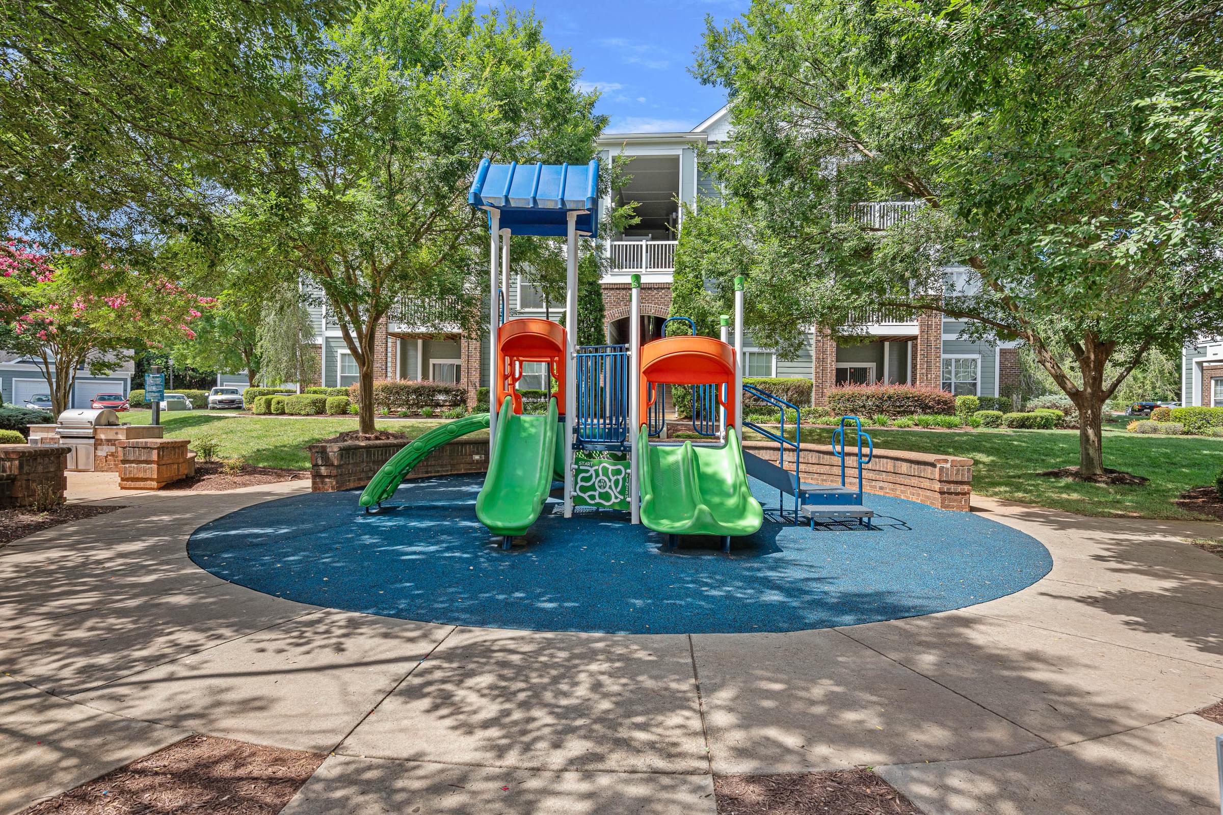 A playground with a blue slide and a green slide.