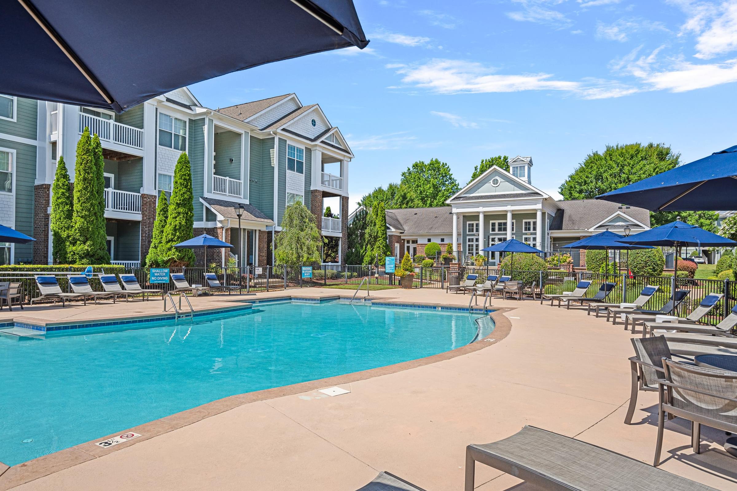 A large swimming pool surrounded by lounge chairs and umbrellas.