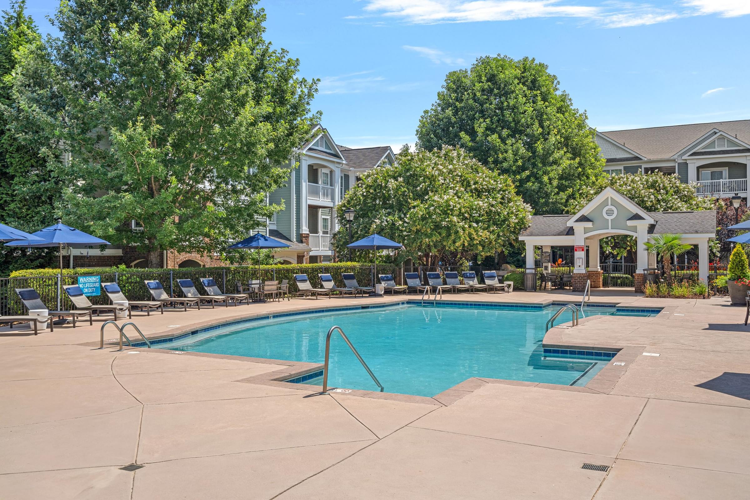 A large swimming pool surrounded by lounge chairs and umbrellas.