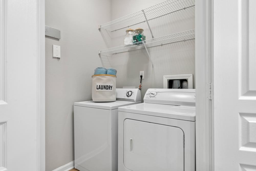 a small laundry room with a washer and dryer and a shelf above it