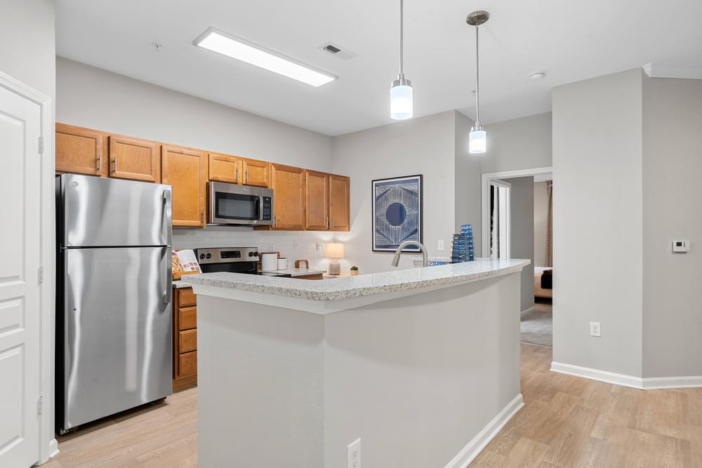 an open kitchen with a large island and stainless steel refrigerator