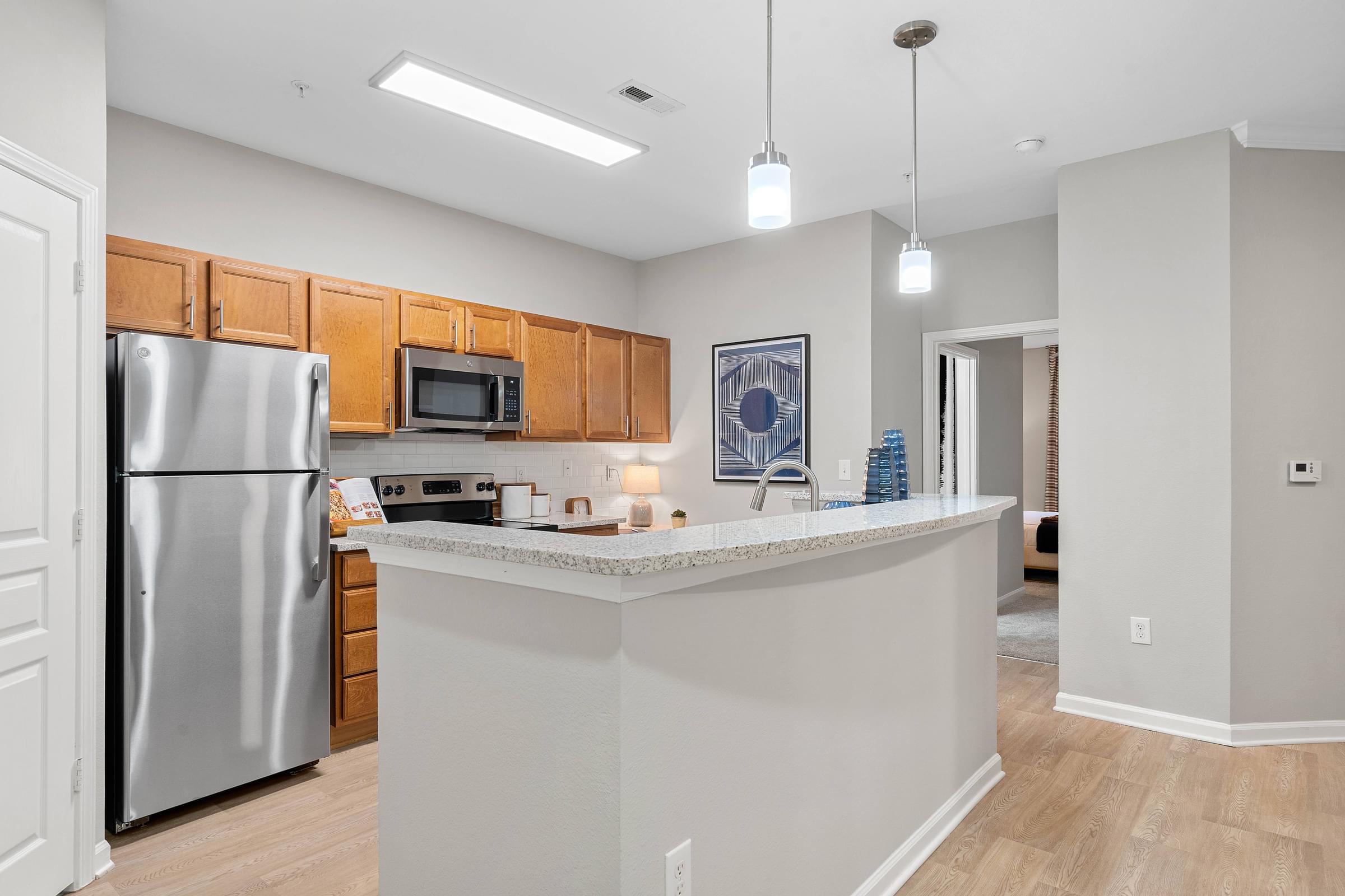 an open kitchen with a large island and stainless steel refrigerator