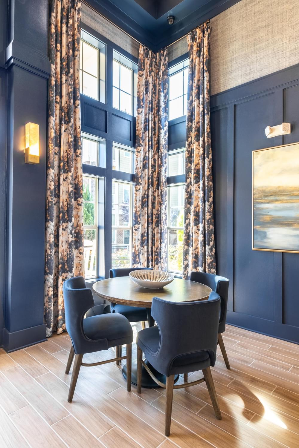 a dining room with navy blue walls and a round dining table with four blue chairs