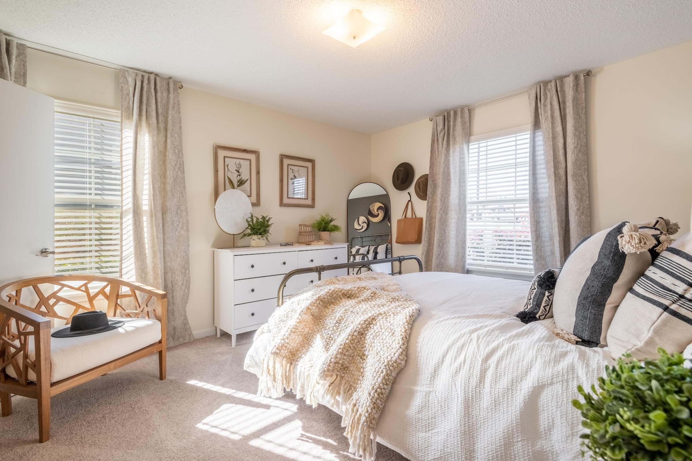 A bedroom with a bed, dresser, and chair