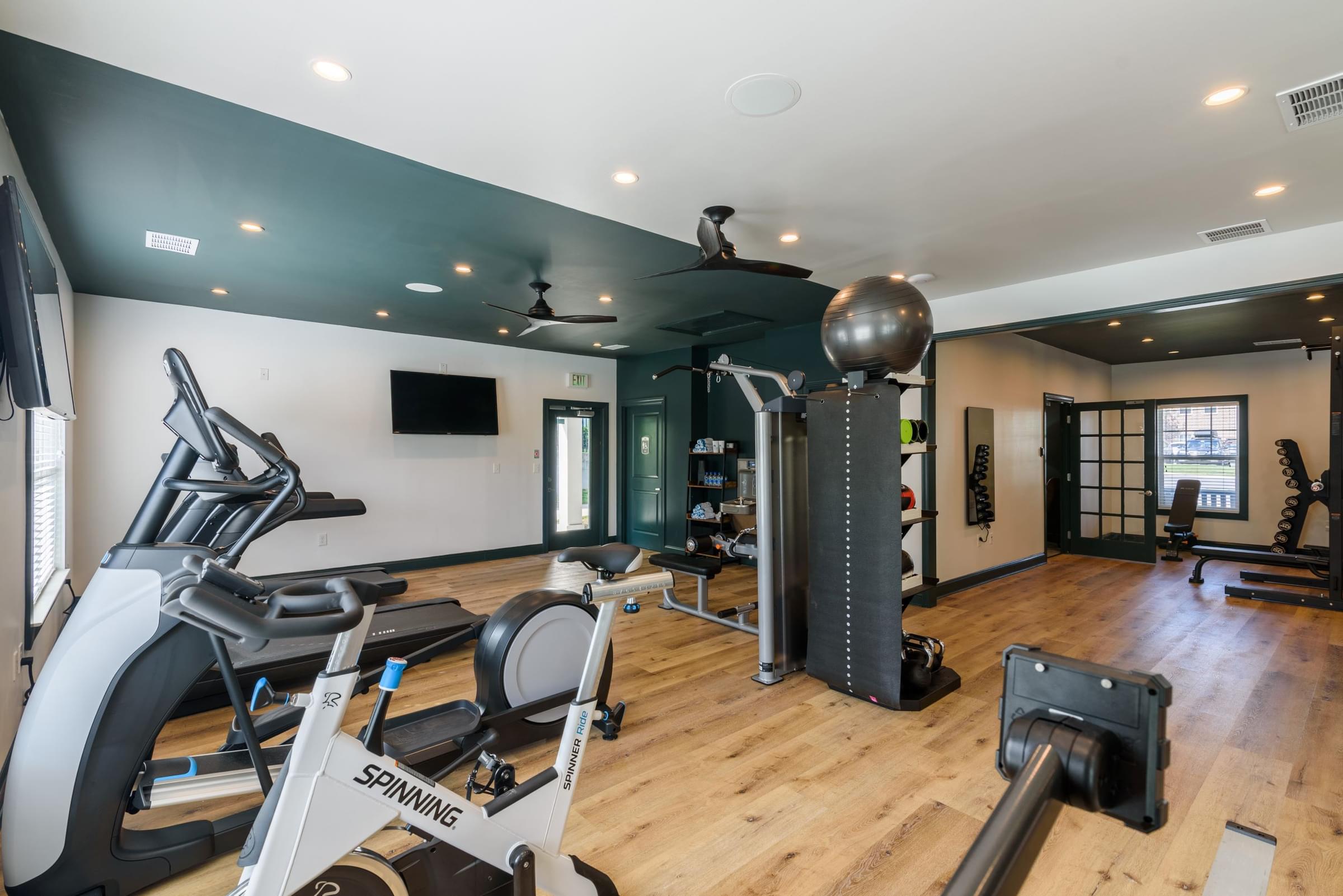 a gym with exercise equipment and weights on a wooden floor