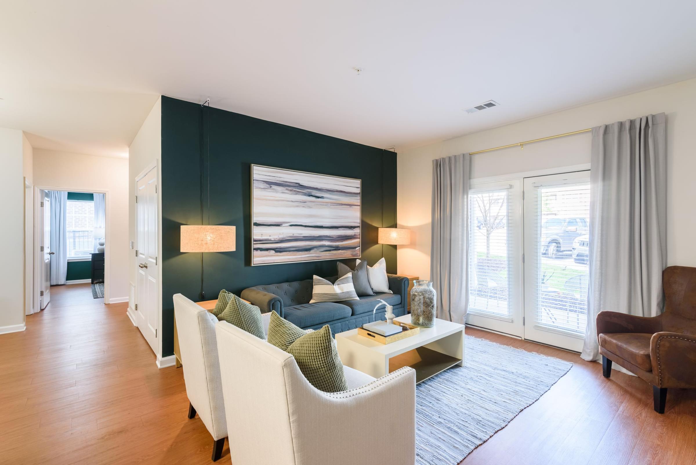 A living room with a white couch and a large painting on the wall.