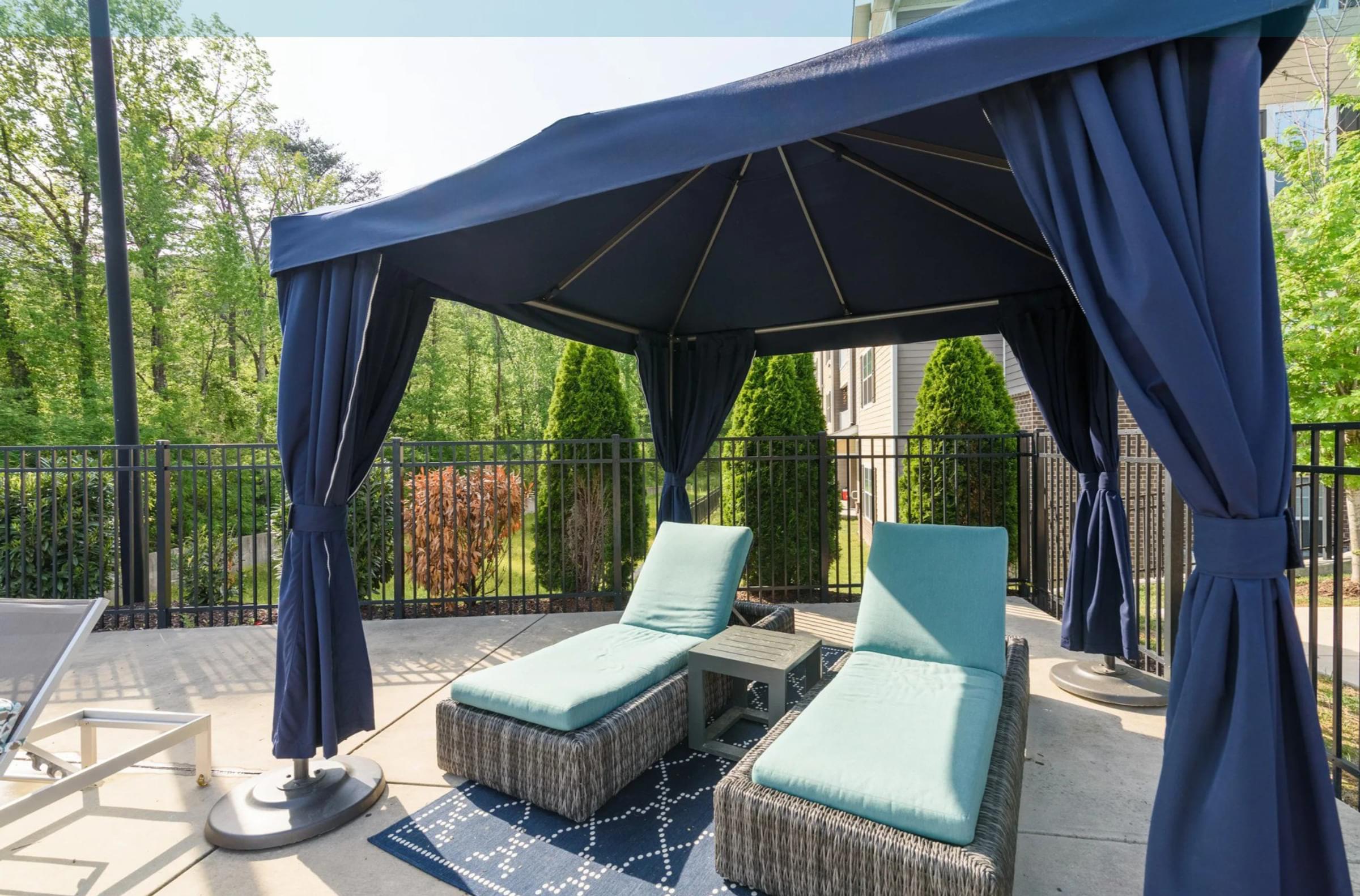 A blue canopy is over a patio with two chairs and a table at Hawthorne at the Hollow apartments in Soddy-Daisy, TN.