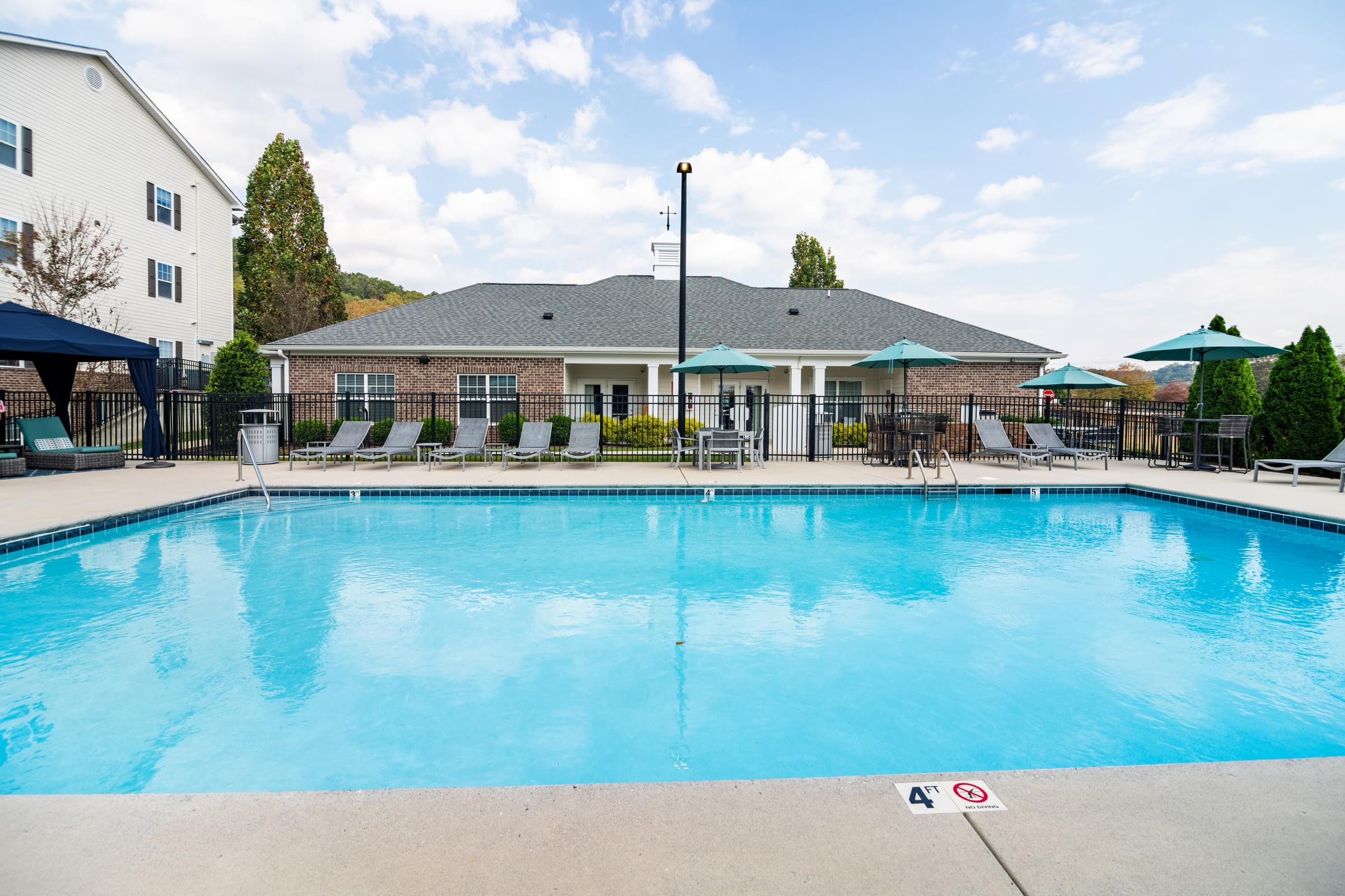 A large swimming pool with a blue tiled edge and a white building in the background.