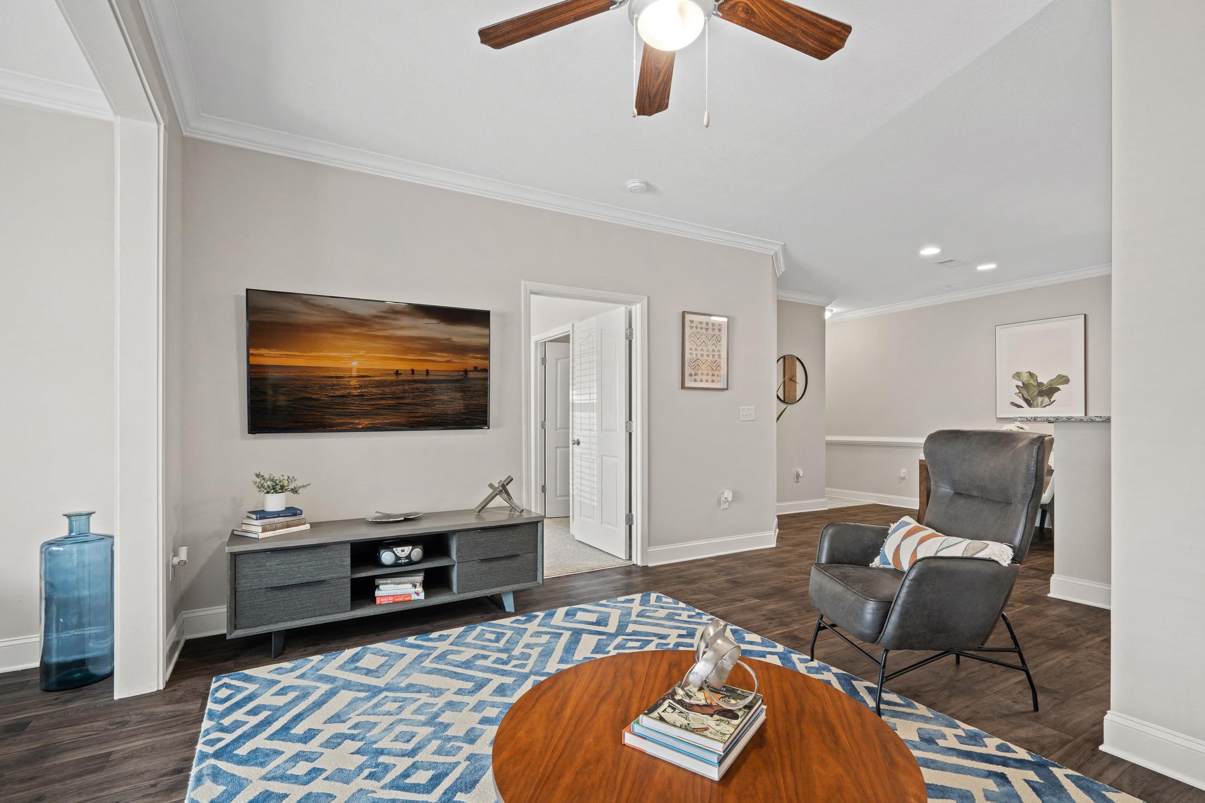 A living room with a ceiling fan and a painting on the wall