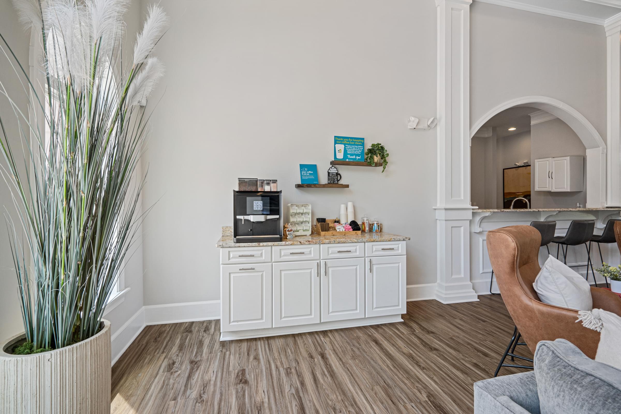 a room with a coffee bar and a kitchen in the background