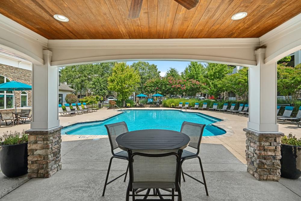 a patio with a table and chairs and a pool in the background