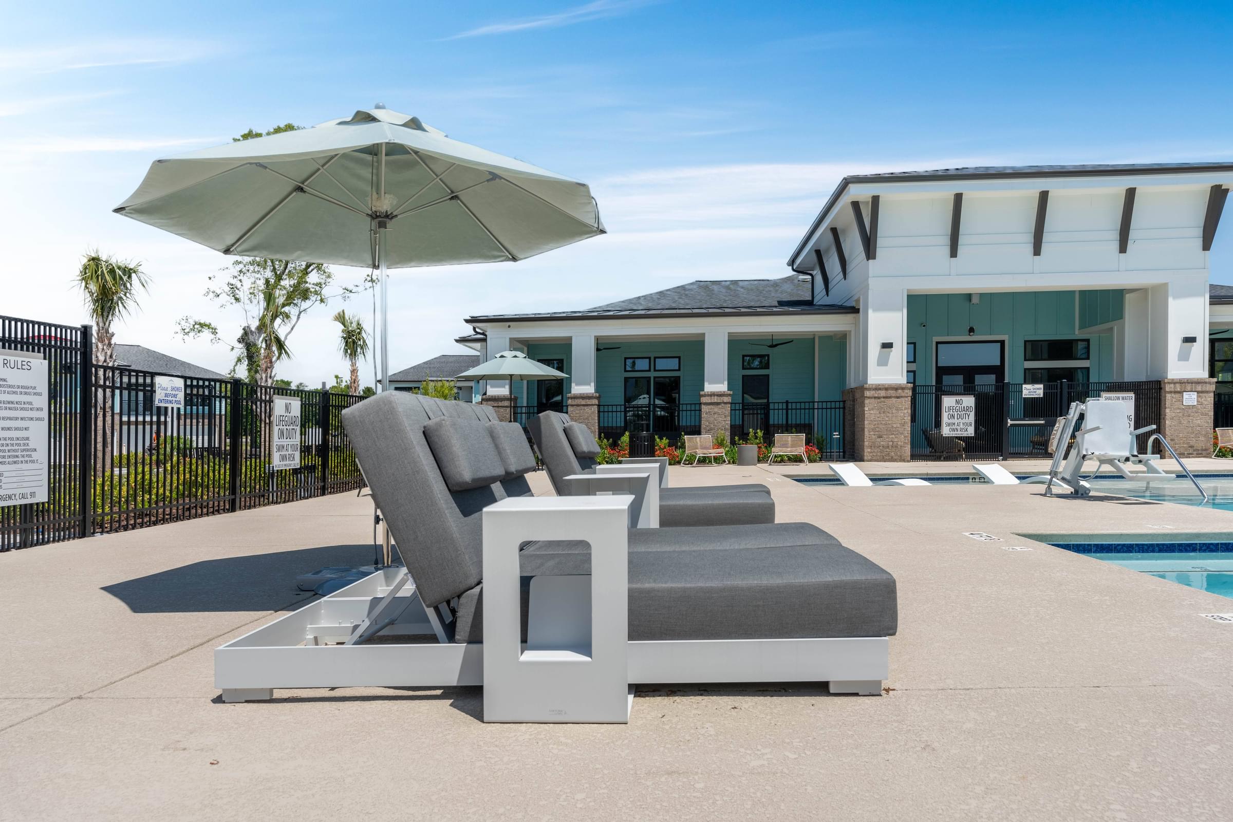 a patio with chairs and umbrellas and a pool in front of a house